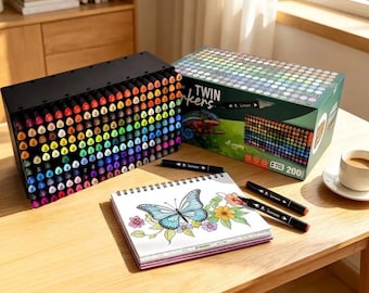 May include: A set of 200 twin markers in a black rectangular organizer, a matching green cardboard box labeled Twin Markers, and a spiral-bound sketchbook featuring a colored butterfly and flower illustration with two black markers resting on top.