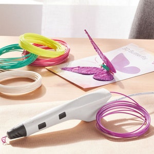 Pu&ograve; includere: Una penna per stampa 3D bianca con punta e pulsanti neri, accanto a una bobina di filamento viola. Sono presenti anche bobine di filamento colorate in verde, giallo, rosa e bianco. Una farfalla 3D viola parzialmente completata &egrave; su una carta.