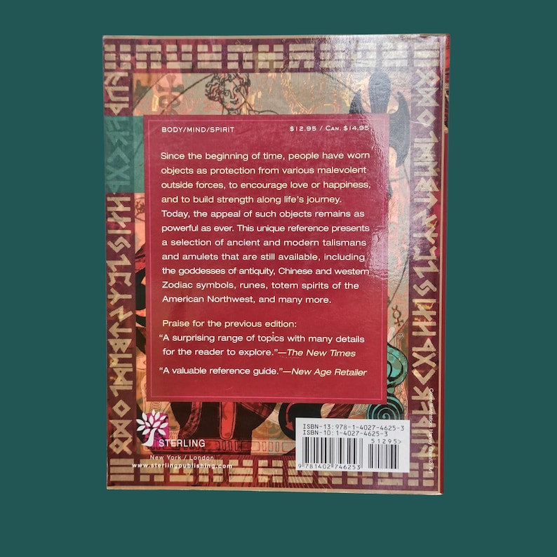 K&ouml;nnte beinhalten: Ein Buchcover mit rotem Hintergrund und goldenen Akzenten. Der Text enth&auml;lt "BODY/MIND/SPIRIT" und eine Beschreibung antiker Talismane und Amulette. Das Backcover enth&auml;lt auch Text von "The New Times" und "New Age Retailer".