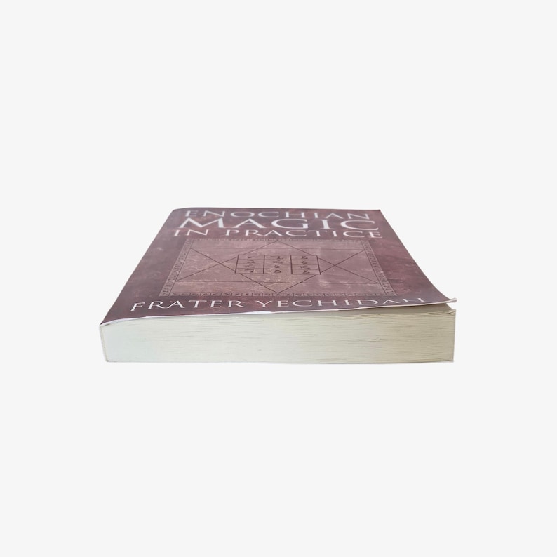 May include: A book titled "Enochian Magic in Practice" by Frater Yechidah. The book has a brown cover with a geometric design and text in a serif font. The book's pages are white, and the spine is visible.