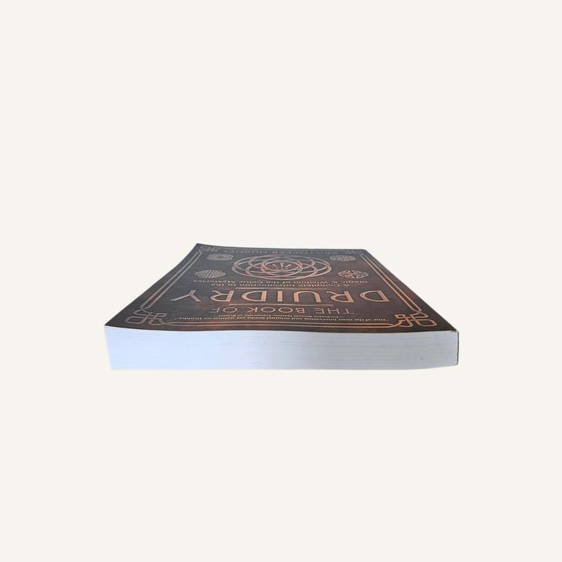 Op de afbeelding: Een hardcover boek getiteld "DRUIDRY THE BOOK OF" met een bruine kaft en koperkleurige reli&euml;fdesigns. Het boek ligt plat en toont de kaft en de titel.