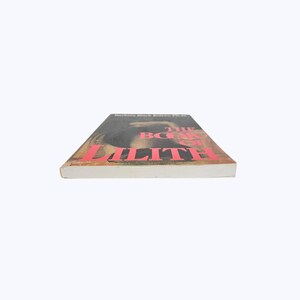 Pode incluir: Um livro de capa dura intitulado "The Book of Lilith" de Barbara Black Koltuv, Ph.D. A capa do livro apresenta uma imagem escura com letras vermelhas. O livro est&aacute; sobre uma superf&iacute;cie branca.