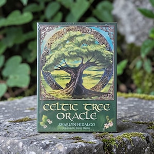 May include: A boxed set of Celtic Tree Oracle cards. The green box has gold lettering and a detailed illustration of a tree within a circular Celtic design. The text on the box reads "Celtic Tree Oracle" and the author's name.