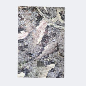 May include: A rectangular book cover featuring a high-resolution, close-up photograph of textured, overlapping snake scales in shades of gray, black, and tan. A barcode is printed near the bottom center, with small text visible below it.