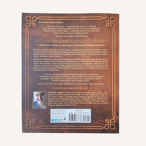 Op de afbeelding: De achterkant van een boek getiteld "Discover the Dappled Grove of Druidry". De omslag is bruin met goudkleurige tekst en decoratieve elementen. De auteur, Kristoffer Hughes, is afgebeeld in een kleine foto. De prijs van het boek is $26,90.