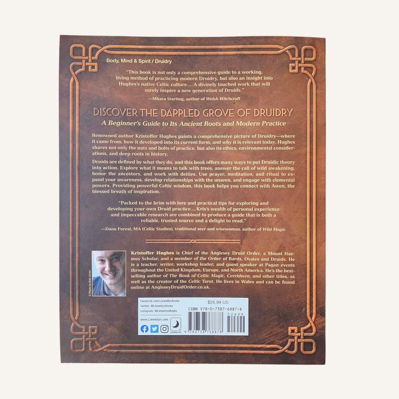Op de afbeelding: De achterkant van een boek getiteld "Discover the Dappled Grove of Druidry". De omslag is bruin met goudkleurige tekst en decoratieve elementen. De auteur, Kristoffer Hughes, is afgebeeld in een kleine foto. De prijs van het boek is $26,90.