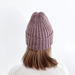 May include: A mauve knitted beanie hat with a ribbed texture.