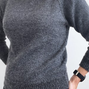 May include: A gray sweater with a round neckline and raglan sleeves.