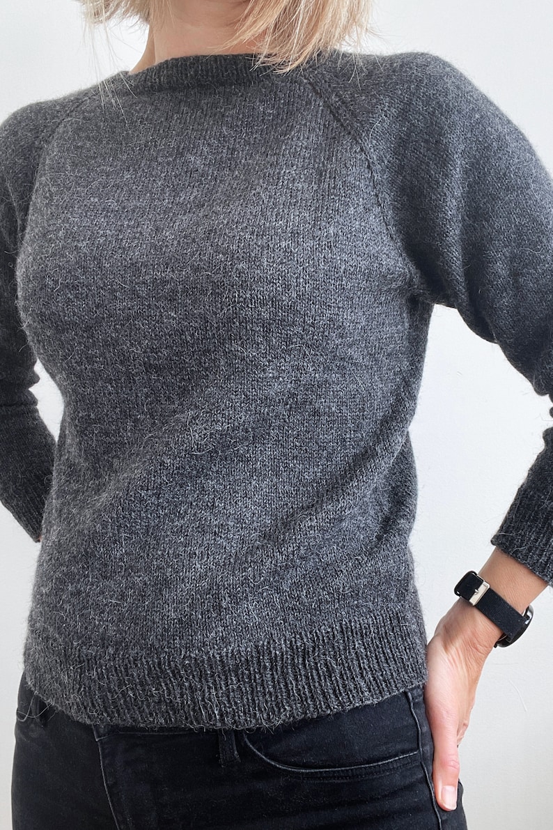 May include: A gray sweater with a round neckline and raglan sleeves.