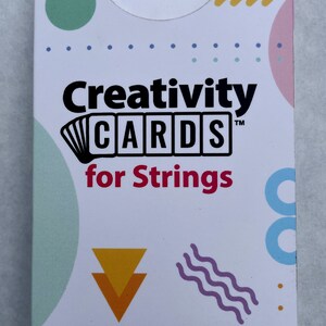 Könnte beinhalten: Eine weiße Schachtel mit dem Text "Creativity CARDS for Strings" in Schwarz und Rot. Die Schachtel hat ein farbenfrohes geometrisches Design mit gelben, grünen, blauen und violetten Akzenten.