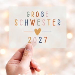 Könnte beinhalten: Eine rechteckige Karte mit dem Text GROBE SCHWESTER in bunten Buchstaben, einem senfgelben Herzsymbol in der Mitte und der Jahreszahl 2027 darunter. Die Karte zeigt zudem die URL WWW.JEKLU.DE sowie weiteren kleinen Text am unteren Rand.