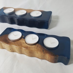 May include: Two wooden candle holders with blue resin. The larger holder has four candle wells and the smaller holder has three candle wells.