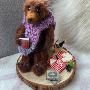 Needle felted Scruffy Bear character, wearing a hand knitted scarf with picnic of cheese and wine accessories