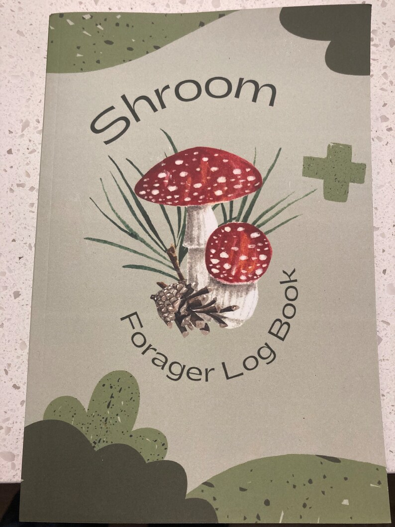 Może przedstawiać: Zielony i brązowy dziennik z tekstem "Shroom Forager Log Book" i rysunkiem dw&oacute;ch czerwono-białych grzyb&oacute;w.