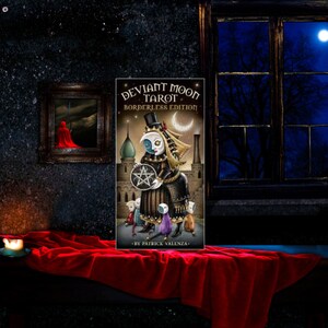 May include: A tarot card from the Deviant Moon Tarot Borderless Edition deck. The card features a dark-skinned woman with a top hat and a pentagram. The card is set against a dark background with a crescent moon and stars.