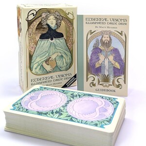 May include: An "Ethereal Visions Illuminated Tarot Deck" set. The set includes a deck of cards, a guidebook, and a box. The box and guidebook feature Art Nouveau-style illustrations in pastel colors. The cards have a light purple and green design.