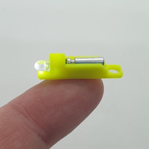 Puede incluir: Una pequeña luz de seguridad amarilla brillante con un reflector plateado. La luz está diseñada para ser fijada a una caña de pescar u otro equipo.