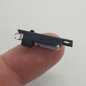 May include: A small black light with a clear lens and the word "LIXIY" printed on the side. The light is held in a person's hand.