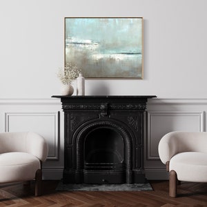 May include: A black fireplace with a white mantel and two white chairs in front of it. A framed abstract painting with blue, white, and brown colors hangs above the mantel.