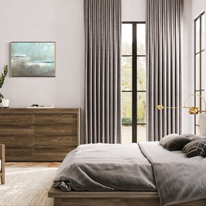 May include: A bedroom with a large bed, a dresser, and a window with gray curtains. The bed has a gray duvet and pillows. There is a painting on the wall above the dresser. The room is decorated in a modern style.