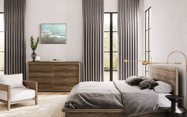 May include: A bedroom with a large bed, a dresser, and a window with gray curtains. The bed has a gray duvet and pillows. There is a painting on the wall above the dresser. The room is decorated in a modern style.