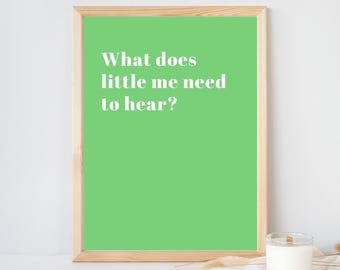 May include: A rectangular wall art print in a light wood frame featuring a vibrant green background with the white text "What does little me need to hear?" printed in a clean, sans-serif font, centered within the frame's borders.
