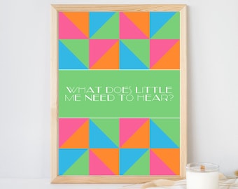 May include: A framed wall art print featuring a geometric pattern of triangles in bright orange, pink, blue, and green. A central horizontal green band contains the white text: WHAT DOES LITTLE ME NEED TO HEAR? The frame is light-colored wood.