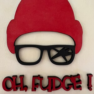 May include: Red wooden hat and black glasses with a lightning bolt design on one lens. The phrase "OH FUDGE!" is written in red letters below the hat and glasses. The design is on a white background.
