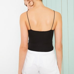 May include: A black spaghetti strap tank top with a fitted silhouette. The tank top is made of a soft, stretchy fabric.