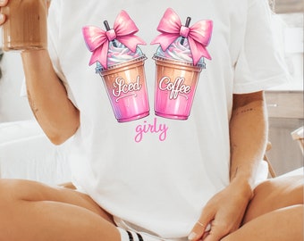 May include: White t-shirt with a graphic of two iced coffee drinks with pink bows and the text "Iced Coffee girly".