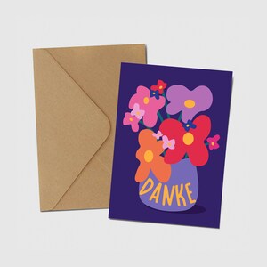 May include: A greeting card with a dark purple background featuring a colorful illustration of flowers in a light purple vase. The word DANKE is printed in yellow on the vase. A plain brown kraft paper envelope is positioned behind the card.