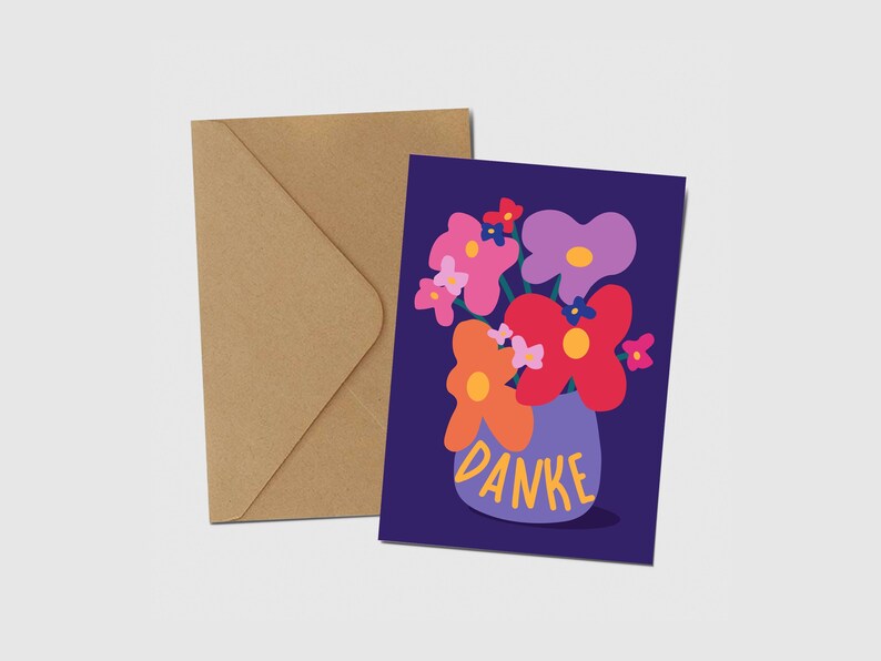 May include: A greeting card with a dark purple background featuring a colorful illustration of flowers in a light purple vase. The word DANKE is printed in yellow on the vase. A plain brown kraft paper envelope is positioned behind the card.