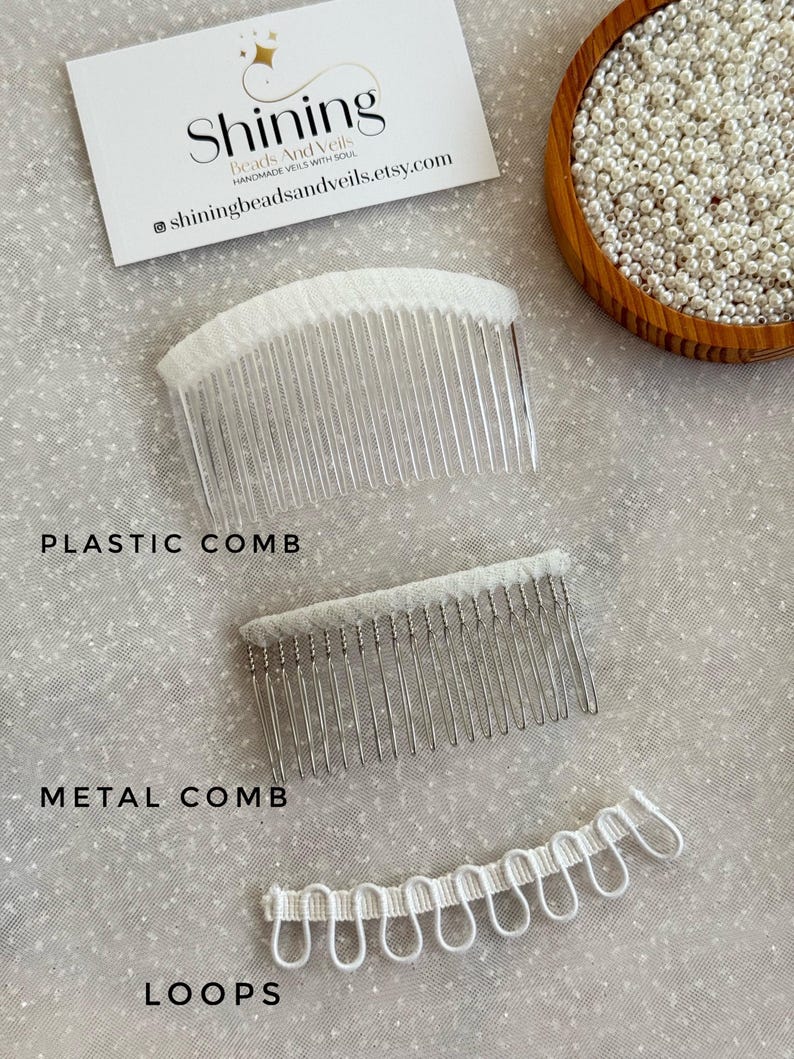 K&ouml;nnte beinhalten: Draufsicht auf drei Brautschleier-Komponenten: ein durchsichtiger Plastikkamm, ein silberner Metallkamm und wei&szlig;e Schlaufen. Eine Visitenkarte und eine Schale mit Perlen sind ebenfalls zu sehen. Der Text "Shining Beads And Veils".