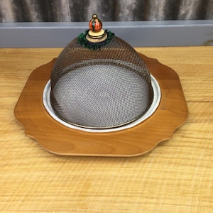 May include: A wooden serving tray with a wire mesh dome lid. The lid has a decorative knob with red, green, and yellow accents.