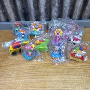 May include: A collection of ten colorful plastic toys packaged in clear plastic bags. The toys feature characters from popular children's shows and movies.