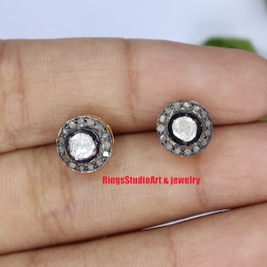 Puede incluir: Un par de pendientes de plata con un centro redondo de diamante blanco rodeado por un halo de diamantes negros más pequeños.