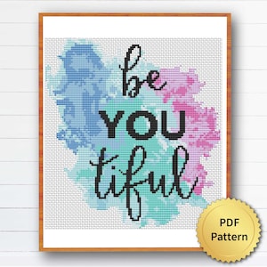 Könnte beinhalten: Ein gerahmtes Kreuzstichmuster mit den Worten "be YOU tiful" in schwarzer Schrift. Der Hintergrund zeigt aquarellartige Spritzer in Blau, Türkis und Rosa. Ein goldfarbenes PDF-Muster-Siegel befindet sich in der unteren rechten Ecke.