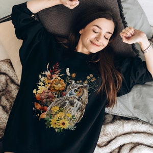 May include: A black sweatshirt with a watercolor design of an owl surrounded by fall-colored flowers.