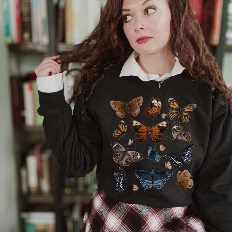 May include: Black sweatshirt with a colorful butterfly print. The butterflies are in various shades of brown, orange, blue, and black.