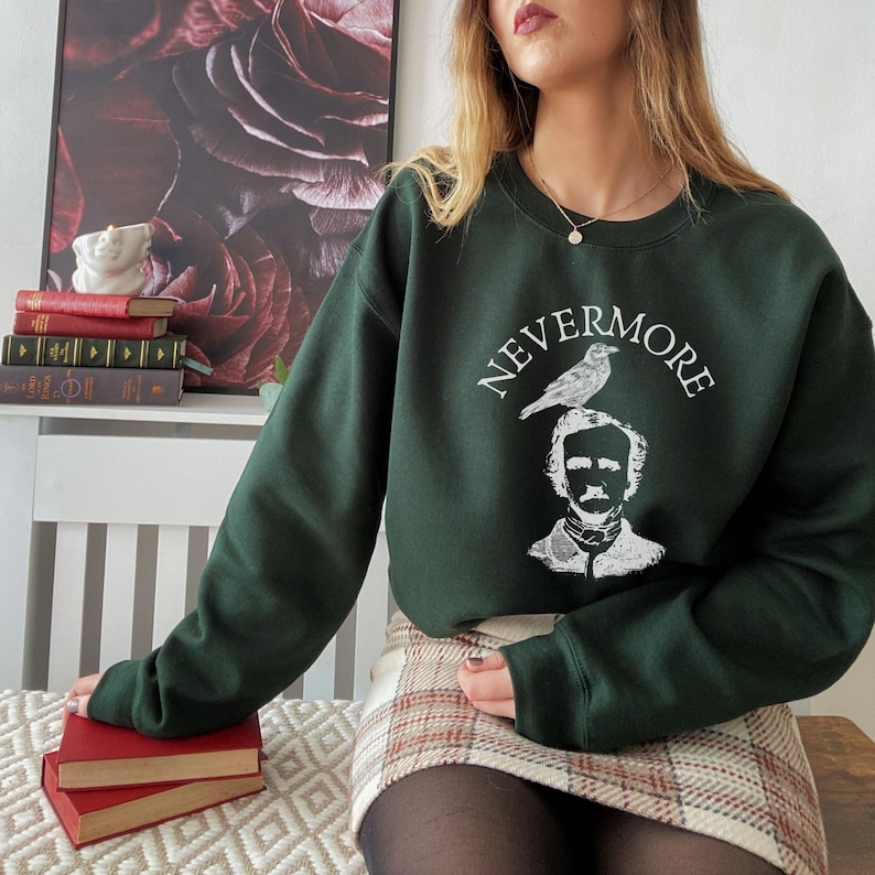 May include: A dark green sweatshirt with the words "Nevermore" and a white illustration of Edgar Allan Poe with a raven perched on his head.