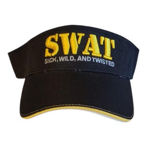 May include: Black visor with the word "SWAT" embroidered in gold, along with the phrase "SICK, WILD, AND TWISTED" in white. The visor has a yellow trim along the edge.