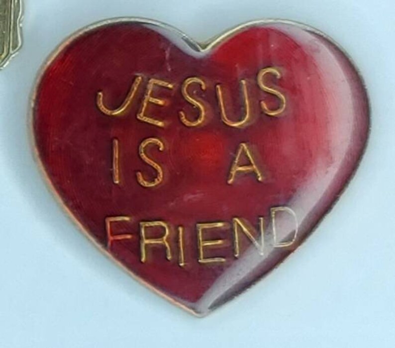 May include: Red heart-shaped pin with gold lettering that reads "JESUS IS A FRIEND".