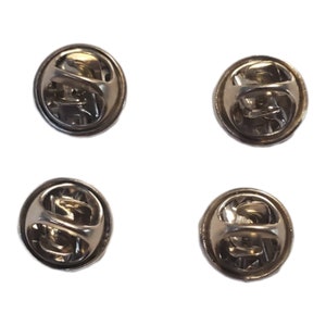 May include: Four silver-toned metal pin backs with a spring-loaded clasp. The pin backs are round and have a smooth surface.