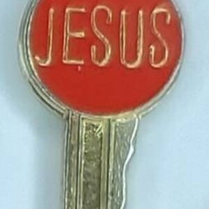May include: A red key-shaped pin with the word "JESUS" in gold lettering.