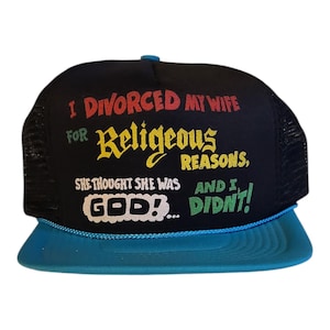 May include: Black trucker hat with a teal brim and a black mesh back. The front of the hat features the text "I DIVORCED MY WIFE FOR Religious REASONS, SHE THOUGHT SHE WAS GOD!... AND I, DIDN'T!" in various colours.