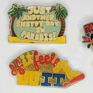 Op de afbeelding: Vijf emaille-pins met humoristische spreuken. De pins zijn geel, rood, blauw en zwart. De spreuken zijn "Eat your heart out I'm retired", "Just another shitty day in paradise", "If it feels good do it", en "Take this job and shove it".