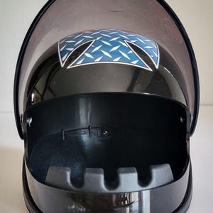 May include: Black ashtray with a hinged, clear lid. The top of the ashtray features a blue and white diamond pattern design. The ashtray has a curved, protective lid and a built-in cigarette rest.