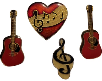 Puede incluir: Un conjunto de pines con temática musical. Dos guitarras rojas, un pin en forma de corazón con notas musicales y un pin de clave de sol. Los pines tienen detalles dorados y negros.