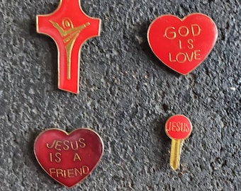 May include: Four red and gold pins with religious messages. The pins are shaped like a cross, a heart, and a key. The cross has a gold figure of a person on it. The heart pins say "God is Love" and "Jesus is a Friend". The key pin says "Jesus".