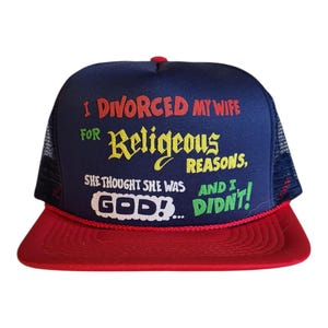 Może przedstawiać: Granatowa czapka typu trucker z czerwonym daszkiem i siatkowym tyłem. Czapka zawiera tekst "I DIVORCED MY WIFE FOR Religious REASONS, SHE THOUGHT SHE WAS GOD!... AND I DIDN'T!" w różnych kolorach.